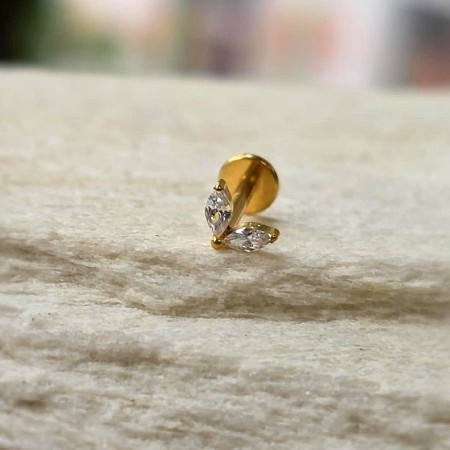 minimalistyczny labret z tytanu ze złota powłoką PVD ozdobiony dwiema cyrkoniami w szlifie markiza, osadzonymi pod kątem, co tworzy efekt subtelnego listka lub skrzydełek