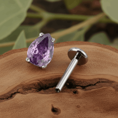 Subtelny i wyjątkowo elegancki labret, którego centrum zdobi cyrkonia w kształcie gruszki o wymiarach 3 × 4 mm. Kamień w odcieniu głębokiej lawendy pięknie odbija światło dzięki szlifowi pear cut