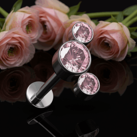 labret typu cluster, ozdobiony trzema różowymi cyrkoniami w subtelnej oprawie, ułożonymi w delikatny łuk.