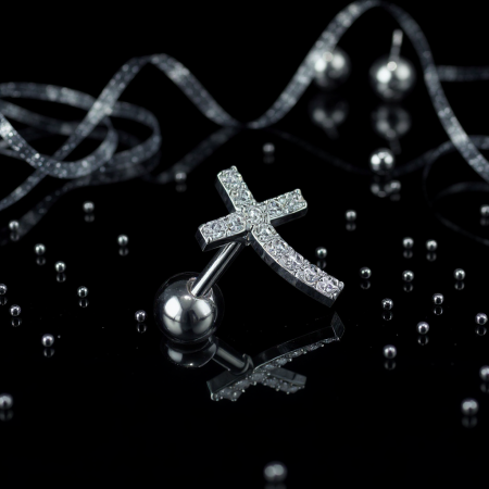 Stylowa i subtelna sztanga do ucha w wersji srebrnej, którą zdobi delikatny krzyż wygięty w łuk wysadzany lśniącymi kryształami.