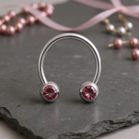 Subtelna i elegancka podkówka do piercingu, ozdobiona różowymi cyrkoniami, które zostały ustawione front facing – skierowane w stronę widoczną w przekłuciu, aby maksymalnie eksponować blask kamieni.