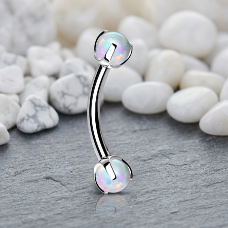 Elegancki banan do piercingu, którego nakrętki ozdobione są 3 mm syntetycznymi białymi opalami, nadając biżuterii subtelny, wielowymiarowy blask.