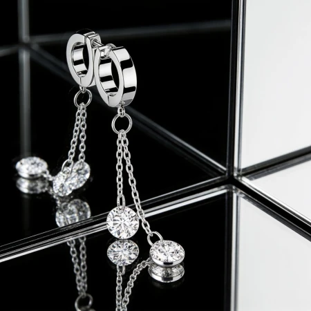 Kolczyk Huggie Double Crystal Dangling – stal chirurgiczna 316L Uroczy kolczyk typu huggie ozdobiony efektowną zawieszką składającą się z dwóch delikatnych łańcuszków zakończonych dużymi, lśniącymi białymi cyrkoniami sześciennymi.