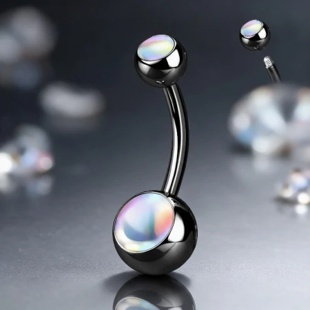 Czarny kolczyk do pępka z opalizującym białym kamieniem Iridescent Stone, zmieniającym kolor zależnie od kąta. Wykonany ze stali 316L z powłoką PVD. Typ gwintu: zewnętrzny.