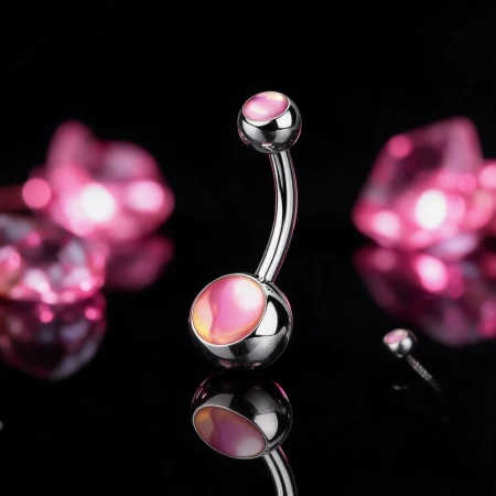 Kolczyk do pępka z opalizującym kamieniem Iridescent Stone w odcieniach różu. Kamień zmienia kolor zależnie od kąta obserwacji. Wykonany ze stali chirurgicznej 316L. Typ gwintu: zewnętrzny.